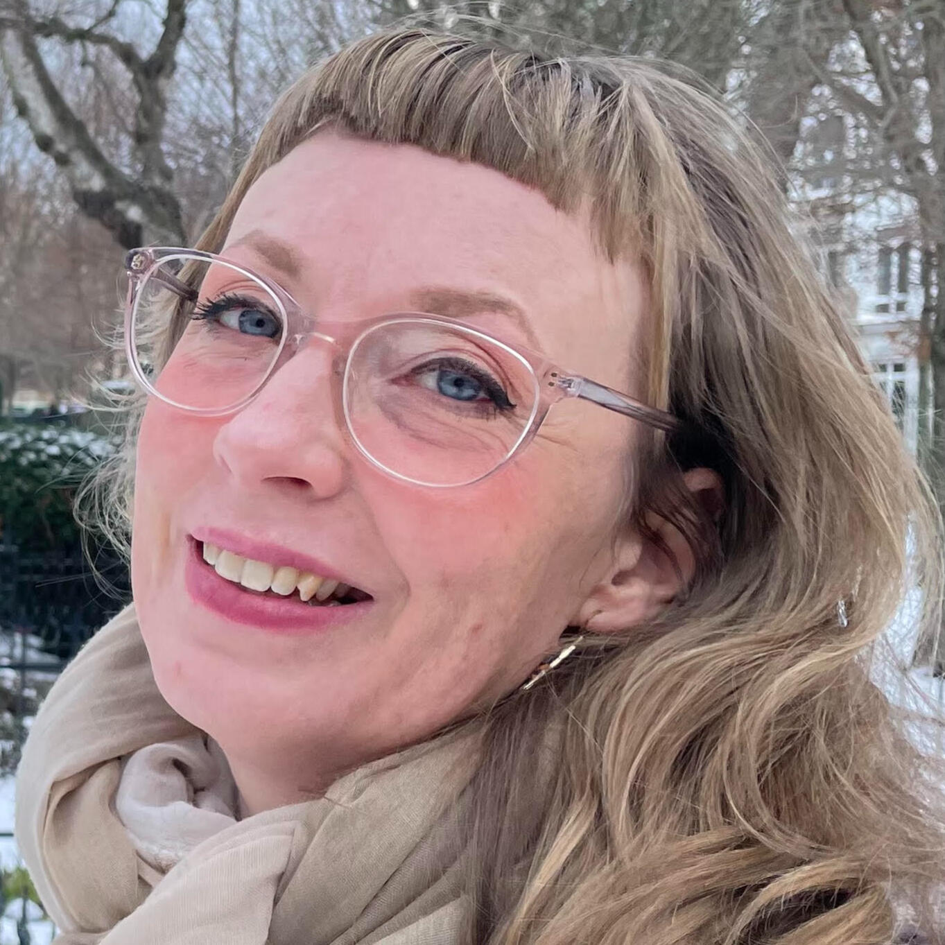 Yoga Kendra Malmö Taoist yoga, Yin yoga, Radiant Lotus Qigong, Sound Healing, Classic Japanese Reiki close-up portrait of a smiling woman with blue eyes, glasses, and short bangs.