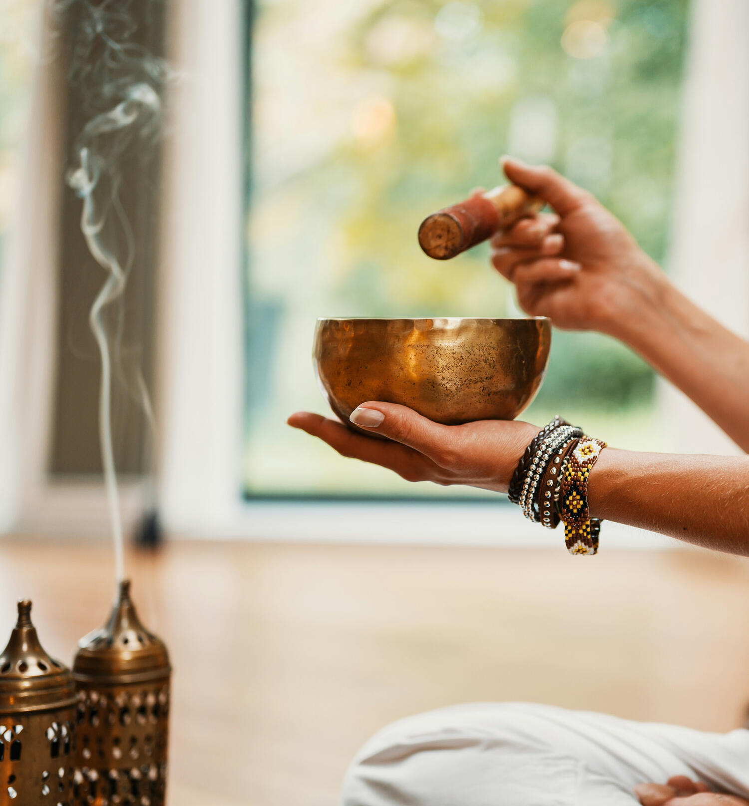 Yin & Soundhealing Yoga Kendra Malmö Person holding a brass Tibetan singing bowl or sound healing bowl along with a wooden striker