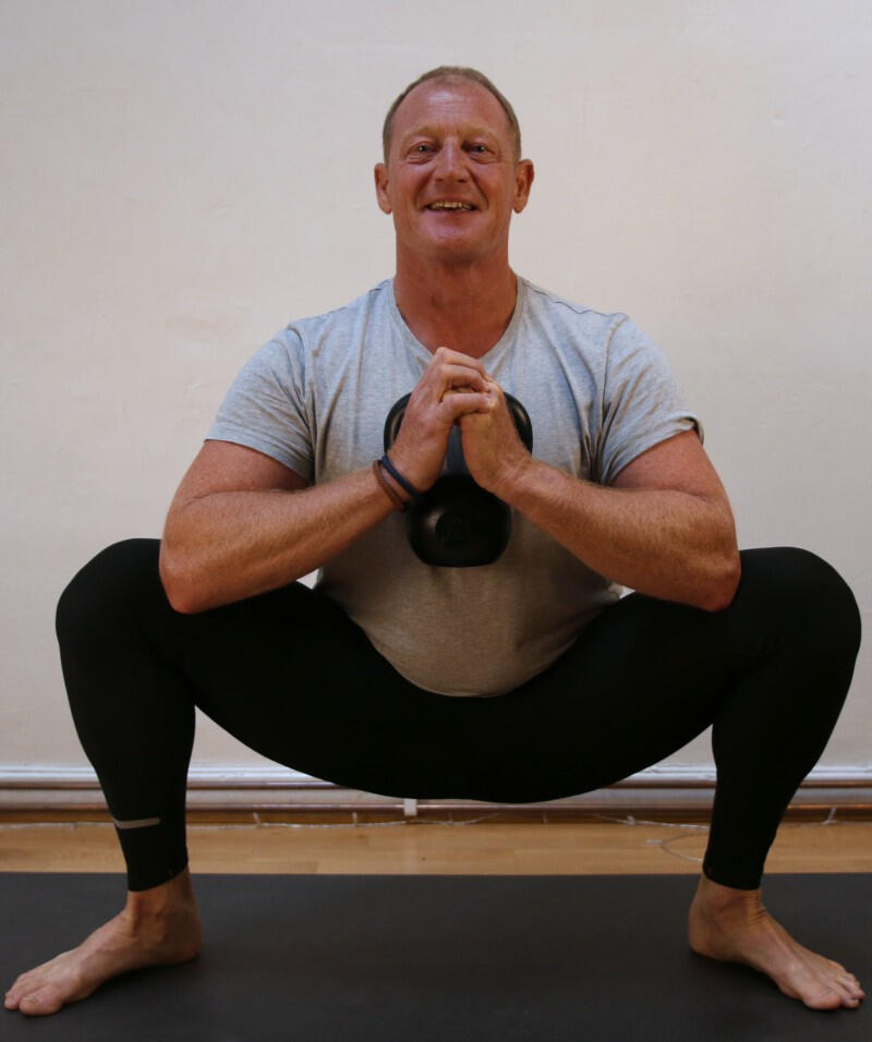 Yoga Kendra Malmö Strength & Mobility Yoga Instructor squatting and holding a weight